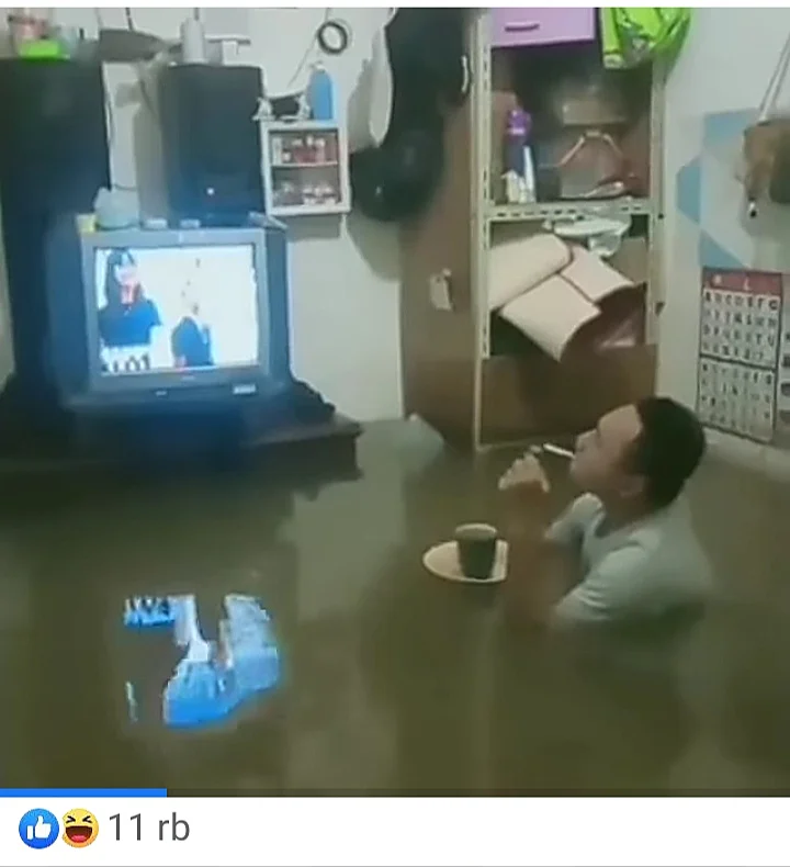 Maling banjir di dalam rumah dengan seseorang menonton TV sambil menikmati minuman.